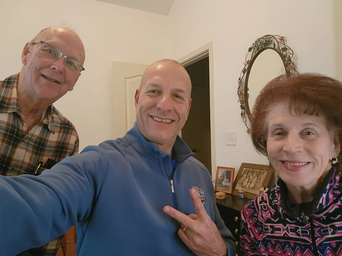 Capital City Roofing project manager Charlie Mandt celebrating a completed roof replacement with happy homeowners